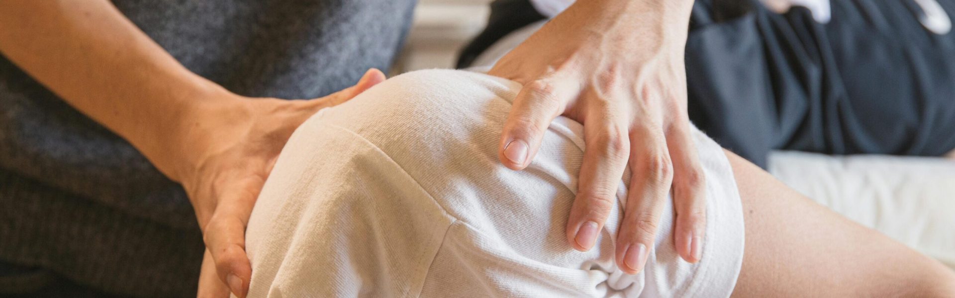 Crop anonymous medical specialist rubbing shoulders of male client lying on couch in medical salon