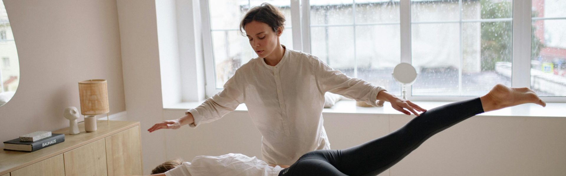 Massage therapist assisting client with stretching on a massage table in a wellness setting.